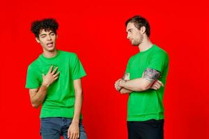 two men in green t-shirts are standing side by side communication isolated background photo