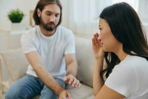 An Asian woman is sad and crying with her male friend at home. Stress and misunderstanding in a relationship between two people and supporting each other's mental and emotional well-being photo