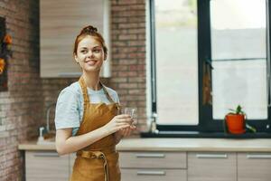 bonito mujer Bebiendo agua cocina Departamento cocina utensilios interior estilo de vida foto