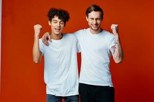 dos alegre amigos en blanco camisetas son en pie siguiente a equipo emociones foto