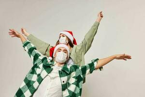 Men and women in New Year's hats on a light background are gesturing with their hands photo