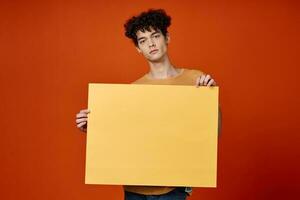 emotional man with curly hair yellow poster in hands photo