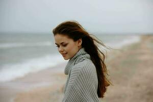 portrait of a woman in a sweater flying hair by the ocean tourism Lifestyle photo