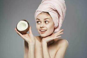 Emotional woman with a pink towel on her head coconut in the hands of tropical fruits clean skin photo