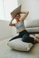 Teenage girl smile everyone sits at home near the couch and tosses up pillows, fun game and happiness without filters, copy place photo