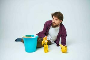 A man lies on the floor with a bucket of detergent cleaning service light background photo