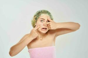 woman in a pink towel squeezes out black dots on her face light background photo