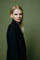 The young model turns and looks at the camera over her shoulder. Cool banner offer. A girl poses in isolation in a suit in a studio with a green background photo