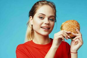 cheerful woman in red t-shirt hamburger in hands fast food blue background photo