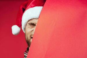 Cheerful man in a santa hat holding a banner holiday red background photo