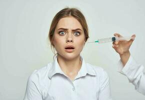 Syringe with liquid and a female patient in a white t-shirt health problems photo