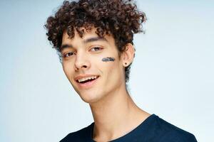 curly-haired guy in a black t-shirt cosmetics on the face clean skin photo