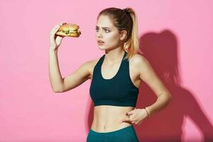 sportive woman workout hamburger fast food diet pink background photo