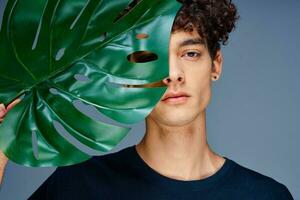 guy with curly hair green leaf close-up studio isolated background photo