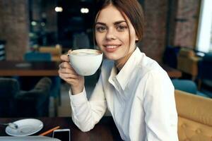 retrato de un hermosa mujer con un taza en mano en un restaurante y interior en el antecedentes foto