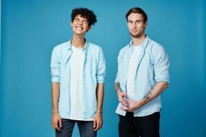 guys in identical shirts and a t-shirt on a blue background friends gesticulate with their hands photo