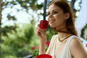 cheerful woman in a white dress drinks coffee outdoors in a cafe Relaxation concept photo