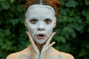 Nice woman anti-aging mask Touch your face with your hands cosmetology bushes in the background photo