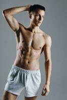guy bodybuilder with pumped up arm muscles on gray background white shorts photo
