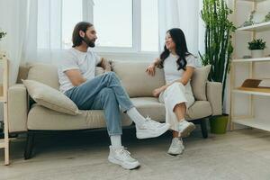 Male and female Asian friends sitting on the couch and having fun talking to each other with a smile having a good time together. Lifestyle in happiness at home photo