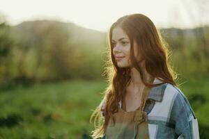 Portrait of a young smiling woman in work clothes checkered shirt and apron in nature in the evening after work photo