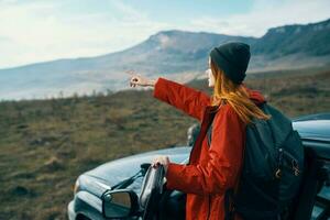 woman hiker in the mountains on nature near the car with a backpack on the back photo
