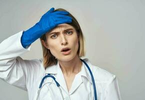 un enfermero en un médico vestido y azul guantes gestos con un estetoscopio alrededor su cuello foto