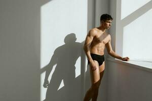 handsome man with pumped up naked body black panties near the window photo