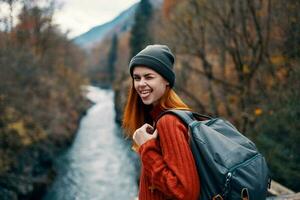 cheerful woman hiker in autumn clothes in the forest near the river photo