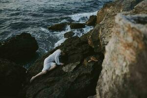 sensual woman in a white dress lying on a stone in a white dress landscape photo