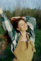 un joven mujer en trabajo ropa y vistiendo un delantal al aire libre disfrutando el puesta de sol y relajante después un difícil días trabajo foto