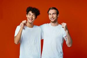 dos hombre en blanco camisetas divertido emociones mano gestos amistad abrazos foto