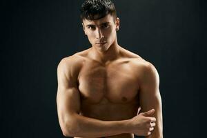 male bodybuilder with a pumped-up body posing against a dark background photo