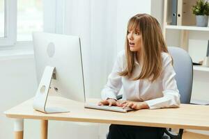 conmocionado trastornado adorable rubia mujer de negocios trabajador Mira a escritorio pensando de problema solución en ligero moderno oficina. empleado trabajo en computadora en línea reflexionando o haciendo decisión. Copiar espacio foto