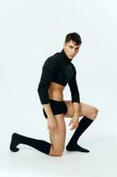 sexy man with an athletic physique kneels in a sweater panties and socks on a light background photo