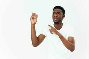 linda africano hombre en blanco camiseta gesticulando con manos en ligero antecedentes foto