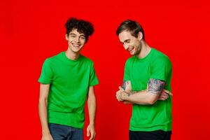 two friends in green t-shirts are standing side by side communication positive red background photo