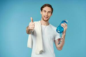 sporty man with tattoos on his arms drink bottle energy workout blue background photo