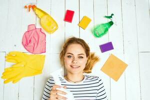 woman in striped t-shirt lies on the floor cleaning supplies detergent housework photo