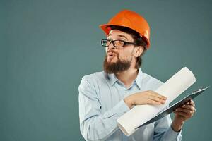 hombre en naranja difícil sombrero planos en manos construcción industria azul antecedentes foto