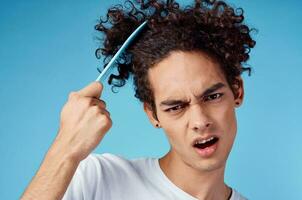 problems with combing hair young guy in t-shirt and combing curls model photo