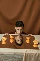 Man at the table with oranges and fabric background photo