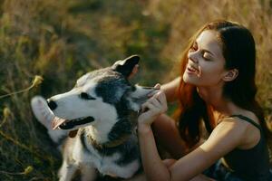 Woman sitting in field with dachshund dog smiling while spending time outdoors with dog friend photo