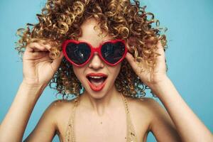 Sweet woman expression of feelings on an isolated blue background, red sunglasses photo