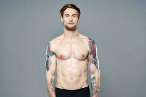 sporty man with a naked torso pumped up press tattoos on his arms photo