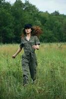 Woman in the field Green jumpsuit black cap jogging on the grass photo