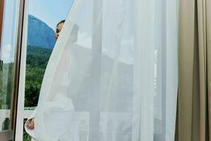 slender woman in a white shirt admires the green nature on the balcony sunny day photo