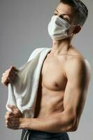sporty man in medical mask towel on shoulders pumped up body photo