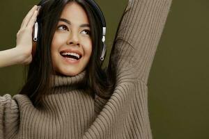 bonito mujer en un suéter escuchando a música con auriculares divertido verde antecedentes foto