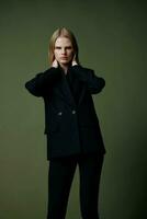 Full-length portrait of a blonde in a classic suit posing on a green background in the studio photo